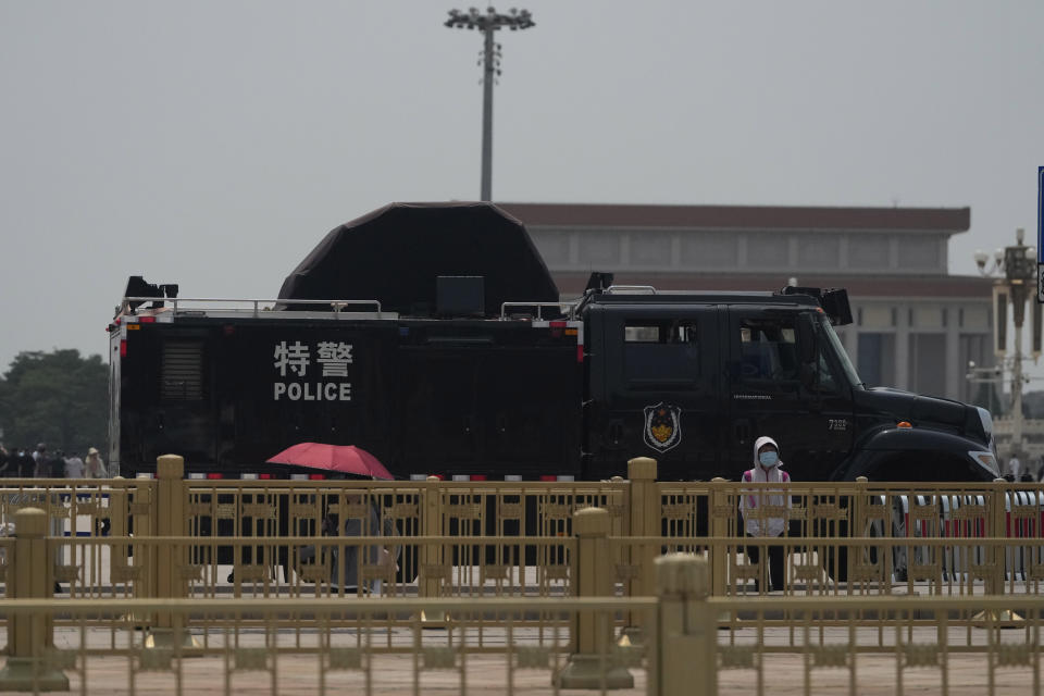 A woman stands near a police vehicle on Tiananmen Square in Beijing, Tuesday, June 4, 2024. Checkpoints and rows of police vehicles lined a major road leading to Beijing's Tiananmen Square as China heightened security on the 35th anniversary of a bloody crackdown on pro-democracy protests. (AP Photo/Ng Han Guan)