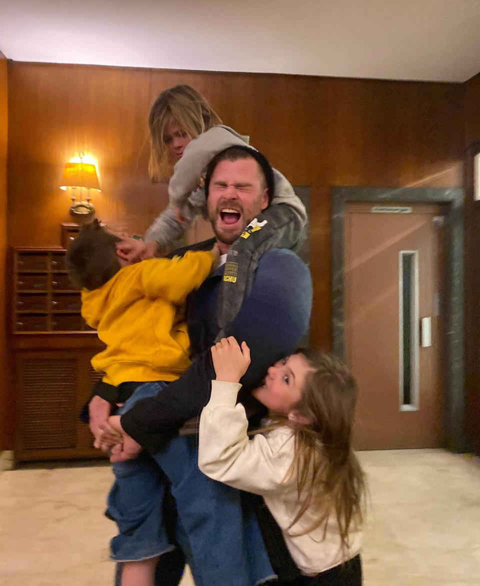 Chris Hemsworth holding two of his kids while his daughter hugs him