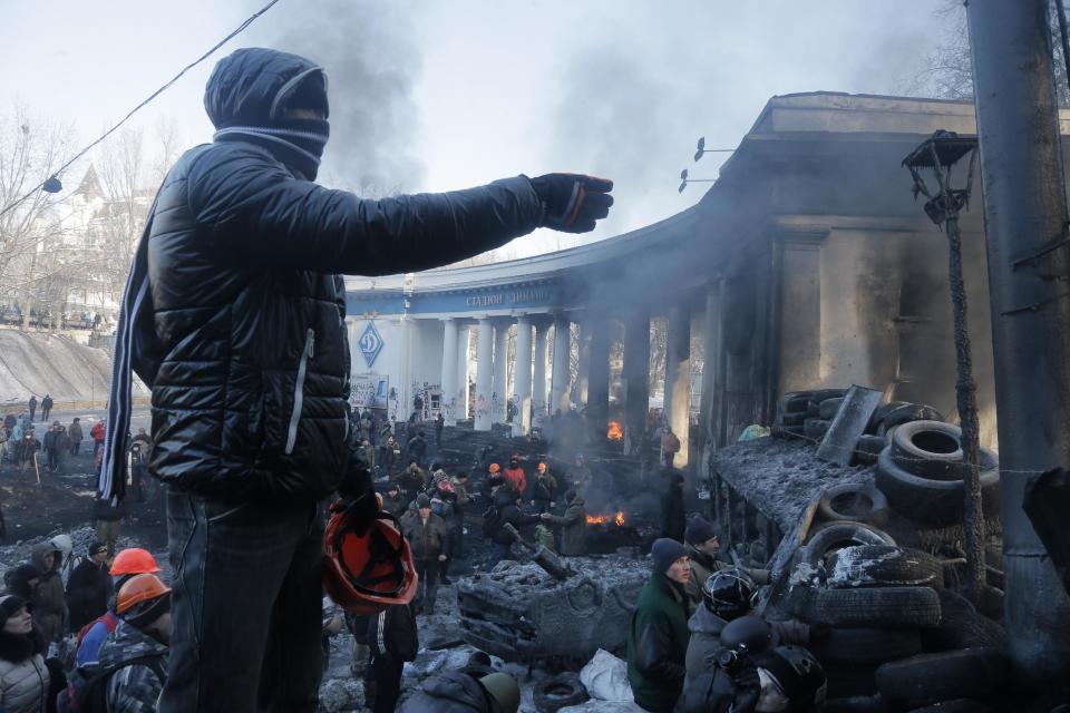 A protester appeals to riot police, with an entrance to Dynamo Kiev soccer club stadium in the background, in Kiev, Ukraine, Jan. 24, 2014. Protesters have seized a government building in the Ukrainian capital while also maintaining the siege of several governors' offices in the country's west, raising the pressure on the government. After meeting with President Viktor Yanukovych on Thursday, opposition leaders told the crowds that he has promised to ensure the release of dozens of protesters detained after clashes with police and stop further detentions. Friday seized a government ministry building in the Ukrainian capital while also maintaining their siege of several governors’ offices in the country’s west, raising the pressure on the government. (AP Photo/Efrem Lukatsky)