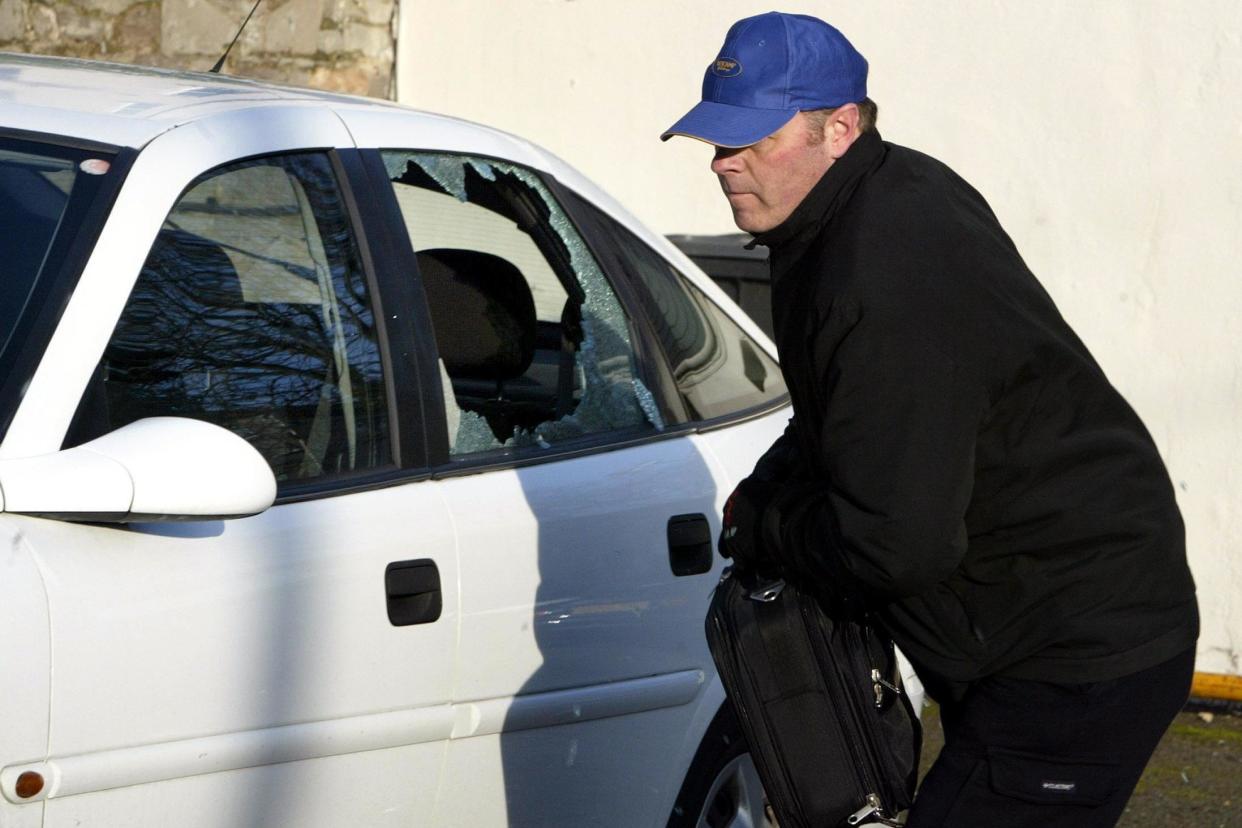 A thief breaks into a car during a mock-up by the Police Service of Northern Ireland in Belfast: PA