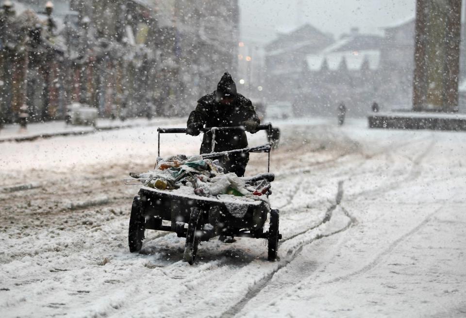 A man pushes his handcart through a snow-covered street during snowfall on a cold winter morning in Srinagar December 31, 2013. Temperatures in Srinagar, which received the season's second snowfall on Tuesday, dipped to -1.4 degrees Celsius (29.5 degrees Fahrenheit), according to India's metrological department website. REUTERS/Danish Ismail (INDIAN-ADMINISTERED KASHMIR - Tags: ENVIRONMENT TPX IMAGES OF THE DAY)