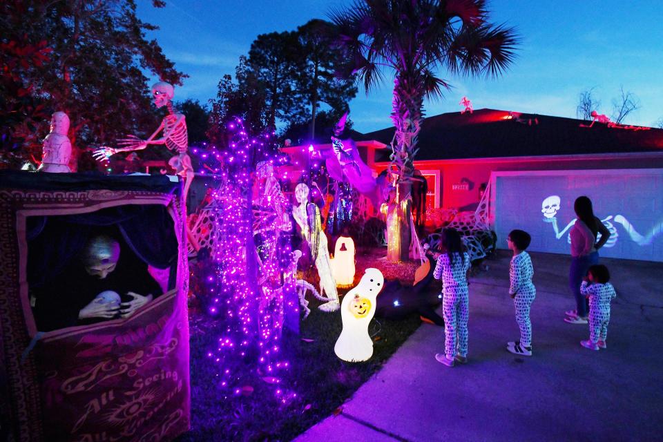 Neighborhood children inspect the skeleton-decorated home of the Thomases. Ashley Thomas is raising funds for St. Jude's Children's Hospital through the elaborate Halloween yard decorations.