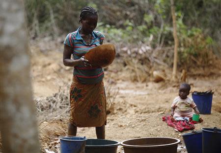 A prospector pans for gold as a child watches her at a new gold mine found in a cocoa farm near the town of Bouafle in western Ivory Coast March 18, 2014. REUTERS/Luc Gnago