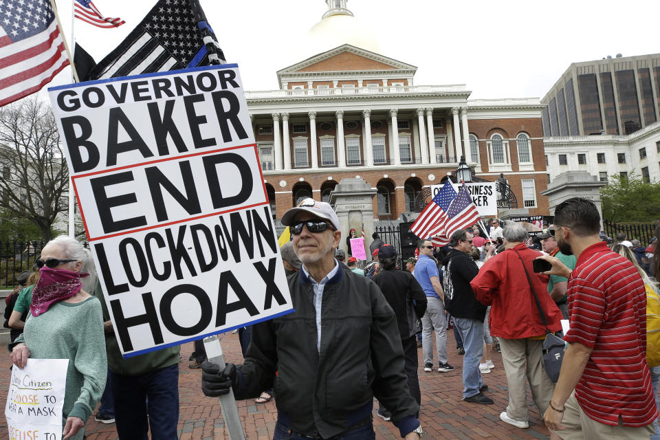 Demonstrators display flags and placards during a protest, Monday, May 4, 2020, in front of the Statehouse, in Boston. Protesters gathered in front of the Statehouse Monday to protest restrictions on movement and businesses prompted by the COVID-19 outbreak. (AP Photo/Steven Senne)