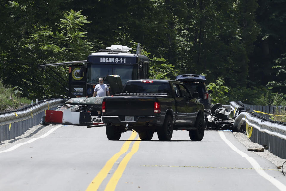 Emergency personnel look over the sight of a helicopter that crashed in Blair, W.Va., on Thursday, June, 23, 2022. A Vietnam-era helicopter was used for tourism flights and crashed along Route 17 in Logan County about 5 p.m. Wednesday. County emergency ambulance service executive Ray Bryant says all six on board were killed.(AP Photo/Chris Jackson)
