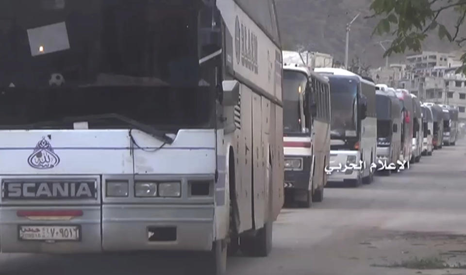 This frame grab from video provided by the government-controlled Syrian Central Military Media, shows buses carrying Syrian rebels and their families, as they leave from Madaya an opposition-held town near Damascus, Syria, Friday, April 14, 2017. The Syrian government and rebels began a coordinated population transfer Friday of about 10,000 people from four towns besieged for years amid the country's bloody, six-year civil war. (Syrian Central Military Media, via AP)