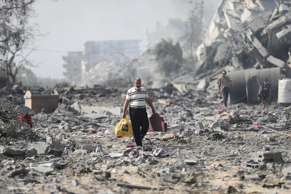 Palestinos caminan entre los restos de los edificios destruidos por los bombardeos israelíes en al-Zahra, a las afueras de la Ciudad de Gaza, el 20 de octubre de 2023. (AP Foto/Ali Mahmoud)