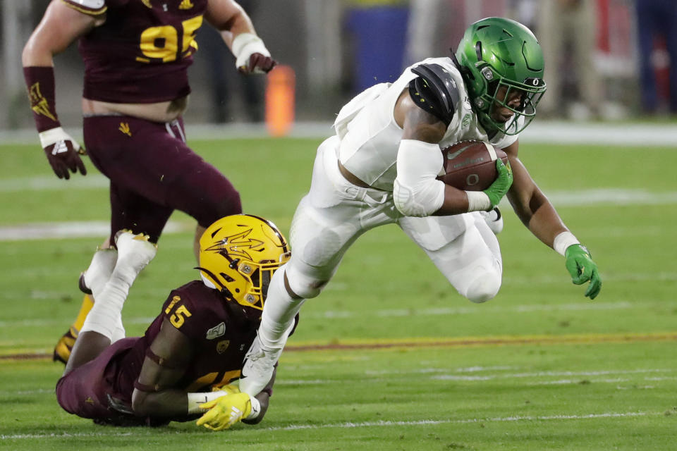 FILE - In this Nov. 23, 2019, file photo, Oregon running back CJ Verdell, right, is tackled by Arizona State safety Cam Phillips (15) during the first half of an NCAA college football game in Tempe, Ariz. The Ducks will have to replace five starters on the offensive line. But Oregon returns significant skill position players, including running back CJ Verdell. (AP Photo/Matt York, File)