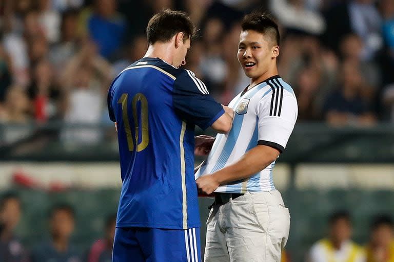 Messi firma un autógrafo para un fanático que invadió el campo durante su partido amistoso contra Hong Kong en Hong Kong el 14 de octubre de 2014