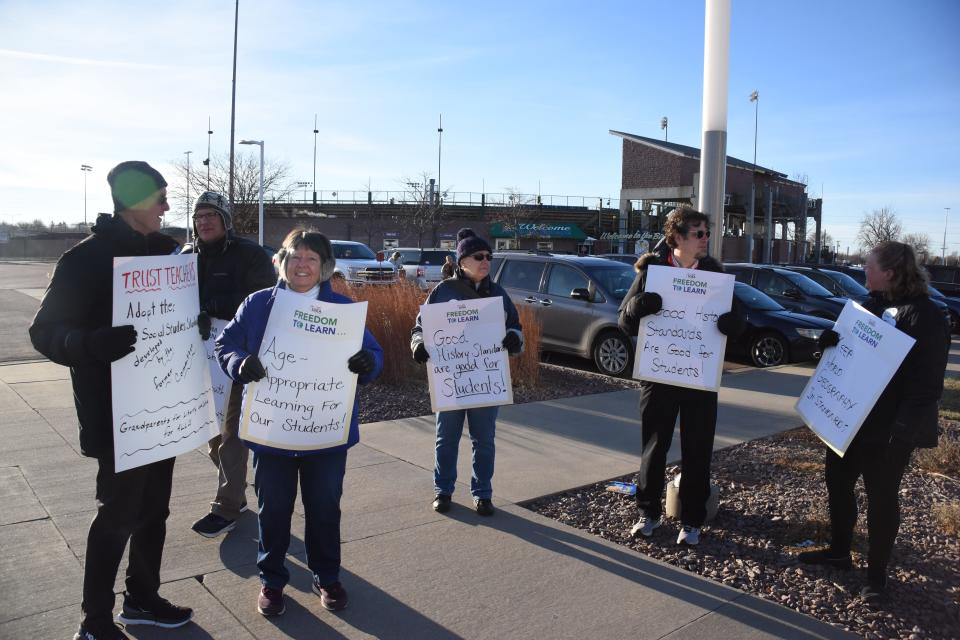 Educators stood outside the Sioux Falls Convention Center ahead of the South Dakota Board of Education Standards meeting in protest of the proposed social studies standards on Nov. 21, 2022. From left to right: Curt Olson, a retired school administrator, holds a sign stating "Trust teachers. Adopt the social studies standards developed by the former commission." Pat McMunigal, a retired special education teacher, holds a sign demanding "Age-appropriate learning for our students." Anita Shearer, a retired school librarian, holds a sign saying "Good history standards are good for students." Tim Eckart, president of the Sioux Falls Education Association, holds a sign stating the same as Shearer. Holly Renken, a seventh grade geography teacher at Patrick Henry Middle School, holds a sign asking to "Keep world geography in standards."