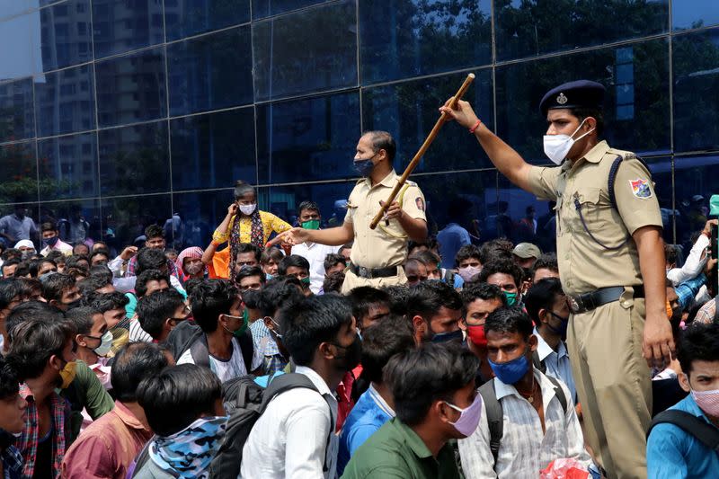 Policemen wearing protective face masks ask people to sit while waiting to enter the Lokmanya Tilak Terminus railway station, amid the spread of the coronavirus disease (COVID-19) in Mumbai