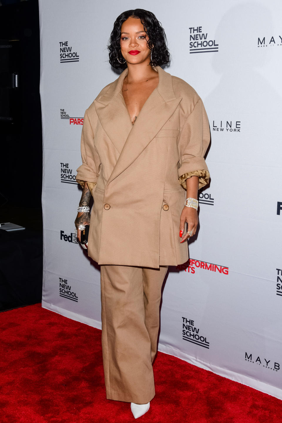 Rihanna on a red carpet wearing a baggy brown suit