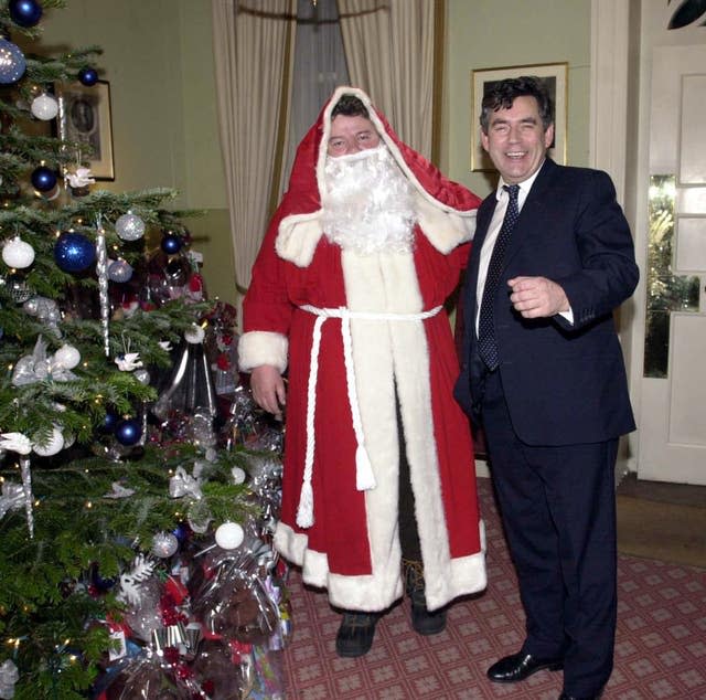 The then Chancellor of the Exchequer Gordon Brown poses with actor Robbie Coltrane, dressed as Santa Claus, at a Christmas party at 11 Downing Street in London on December 3, 2001.