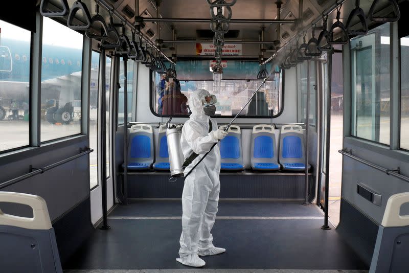 FILE PHOTO: A health worker sprays disinfectant inside a bus to protect from the recent coronavirus outbreak, at Noi Bai airport in Hanoi, Vietnam