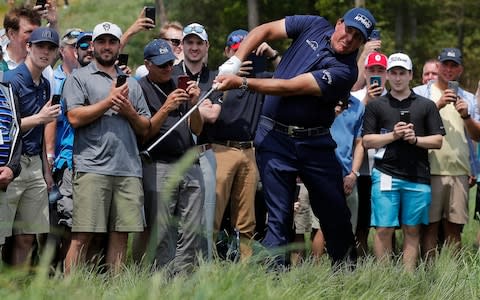 Phil Mickelson draws the eyes and cameraphones of the spectators as he punches out of the tough - Credit: AP