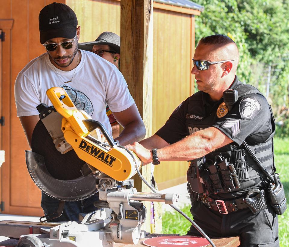 Bryson Davis and an Akron police officer set up a saw for the 'Chop Some Guns' event, Thursday, July 18, 2024, in Akron, Ohio.