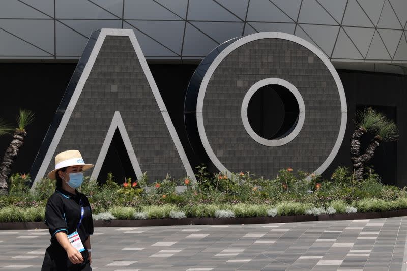 FILE PHOTO: A person wearing a protective face mask walks past an Australian Open logo at Melbourne Park in Melbourne