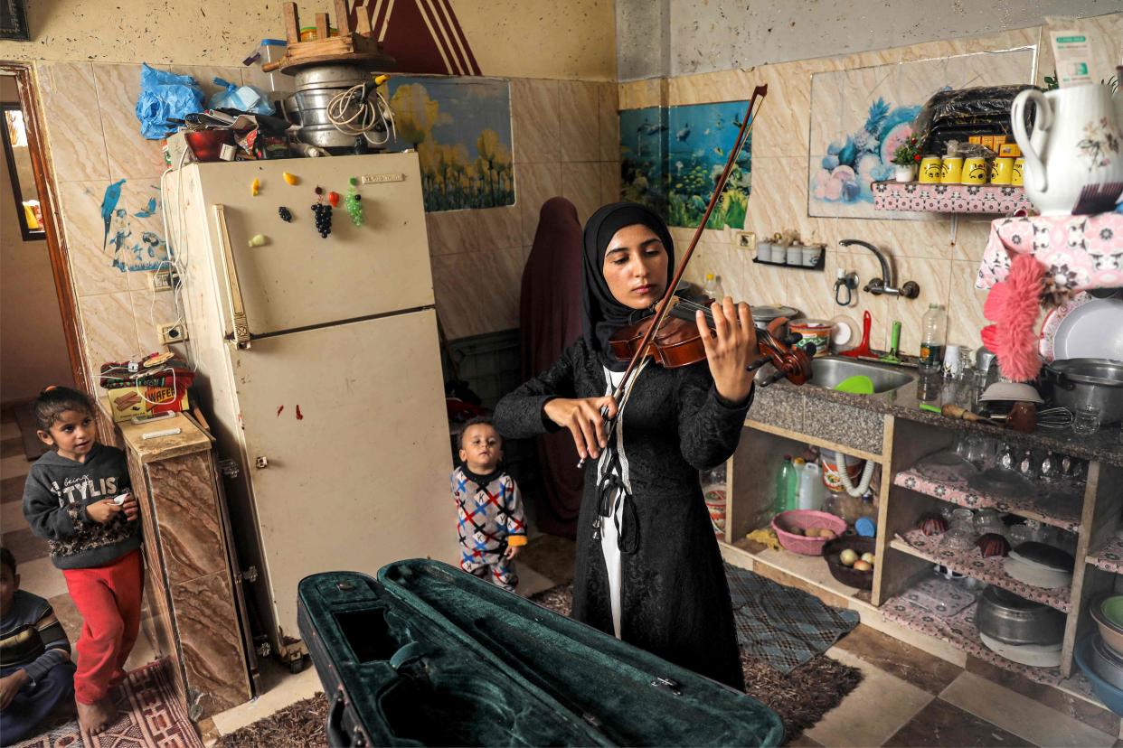 Palestinian musician Jawaher al-Aqraa plays a violin as she stands in the kitchen of her home in Gaza (AFP via Getty Images)