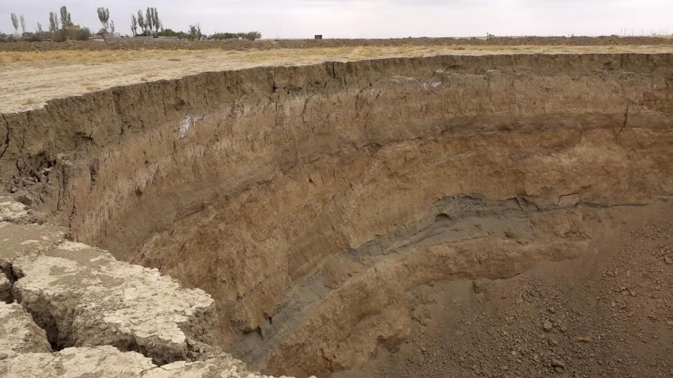 This frame grab from video taken on Aug. 8, 2018, provided by Iranian Students' News Agency, ISNA, shows the edge of a massive hole caused by drought and excessive water pumping in Kabudarahang, in Hamadan province, western Iran. Some sinkholes formed in western Iran are as deep as 60 meters (196 feet). (ISNA via AP)