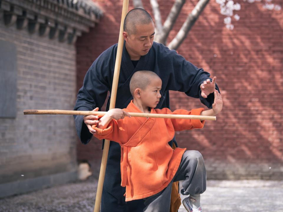 A monk and a child practice Kung Fu underneath blooming cherry blossoms at Shaolin Temple on March 30, 2022