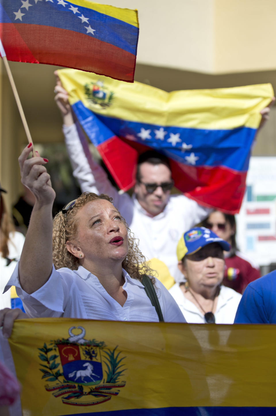 Rosauda Burgos, izquierda, canta el hImno nacional de Venezuela en una manifestación contra el gobierno del presidente Nicolás Maduro en Doral, Florida, EEUU, el martes 18 de febrero de 2014. (AP Photo/Wilfredo Lee)
