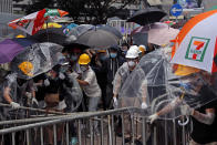 In this photo taken on Wednesday, June 12, 2019, protestors wear masks and helmets and hold umbrellas to protect their identities and provide cover from tear gas and pepper spray, as they clash with police near the Legislative Council in Hong Kong. Young Hong Kong residents protesting a proposed extradition law that would allow suspects to be sent to China for trial are seeking to safeguard their identities from potential retaliation by authorities employing mass data collection and sophisticated facial recognition technology. (AP Photo/Kin Cheung)