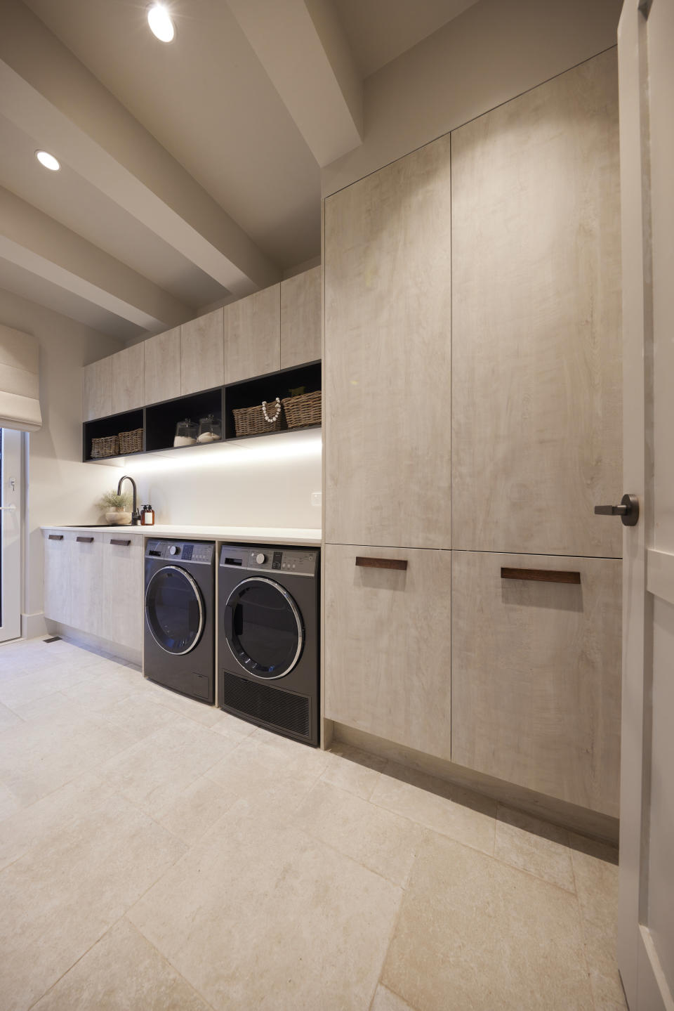 Light wood cupboards on the right with a washer and dryer to the left and shelf space. 