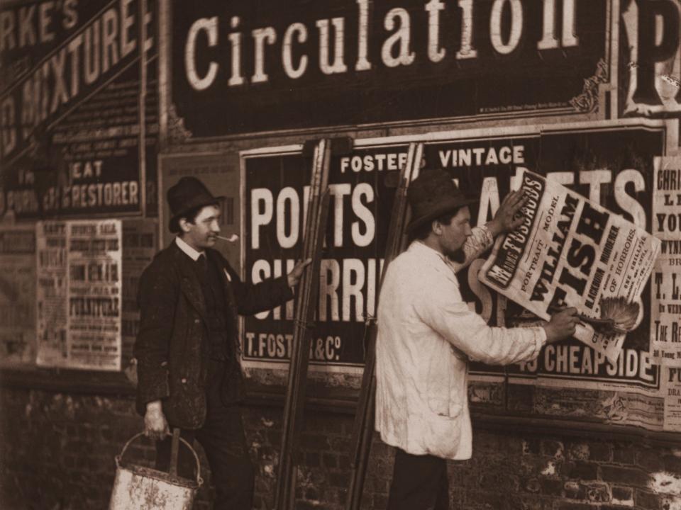 1877: Victorian bill stickers paste placards advertising Madame Tussaud's waxworks museum in London.