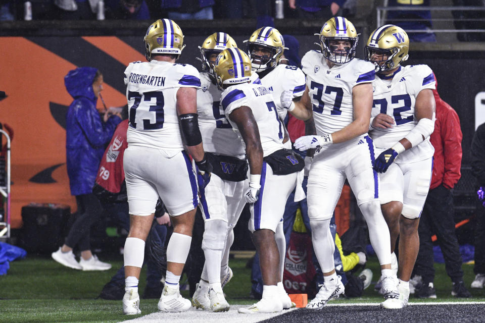 Washington quarterback Michael Penix Jr., second from left, celebrates his touchdown against Oregon State with teammates during the first half of an NCAA college football game Saturday, Nov. 18, 2023, in Corvallis, Ore. (AP Photo/Mark Ylen)