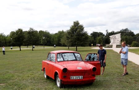 People stand next to Trabant, an East German car, at the Pan-European Picnic Memorial Park in Sopronkohida