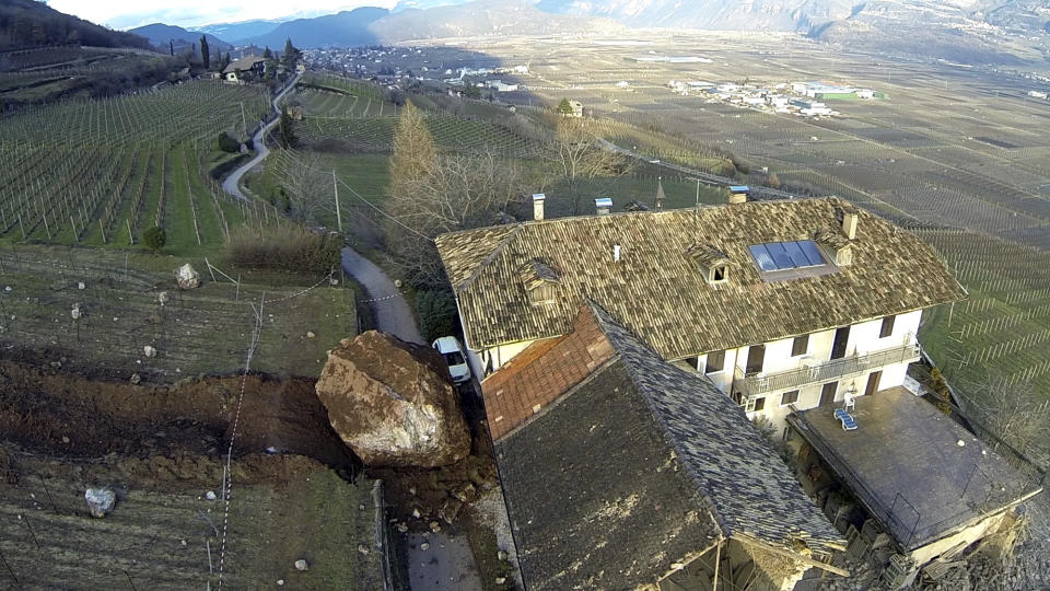 In this photo provided by Tareom.com Thursday, Jan. 30, 2014, and taken on Jan. 23, 2014, a huge boulder is seen after it stopped next to a farm house, while a second giant boulder, which detached during the same landslide on Jan. 21, 2014, missed the house by less than a meter, destroying the barn, and stopped in the vineyard below, in Ronchi di Termeno, in Northern Italy. According to reports, the Trebo family living there was unharmed in the landslide. (AP Photo/Markus Hell, Tareom.com, ho)