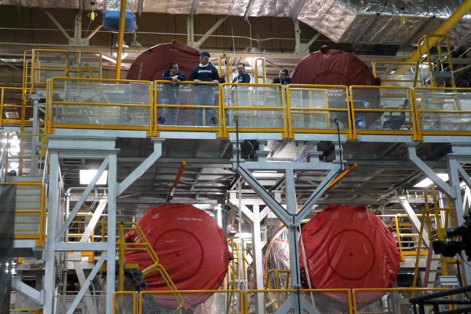 Employees watch speakers as they stand on the scaffolding in front of the four rocket engines that have been attached to the core stage of the Artemis 1 rocket at the NASA Michoud Assembly Center in New Orleans, Monday, Dec. 9, 2019. (AP Photo/Gerald Herbert)