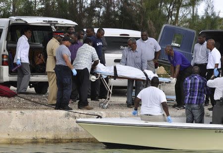 Rescue workers carry from a boat to a hearse the body of one of the victims of a small plane that crashed near the airport of Grand Bahama Island, in East Grand Bahama August 18, 2014. REUTERS/Vandyke Hepburn