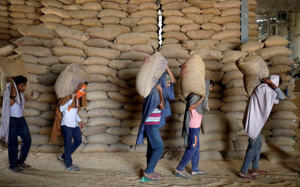 Workers carry sacks of wheat for sifting at a grain mill on the outskirts of Ahmedabad, India - Amit Dave/REUTERS