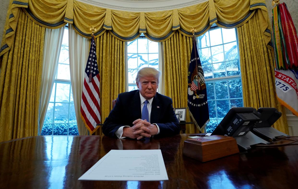 Donald Trump sits at the Resolute Desk (REUTERS)