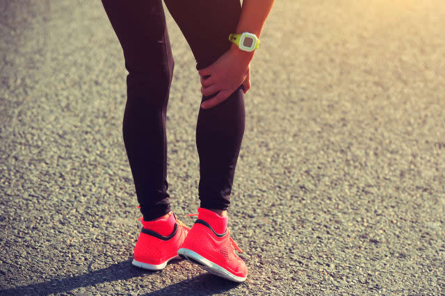 woman runner hold her injured leg on road