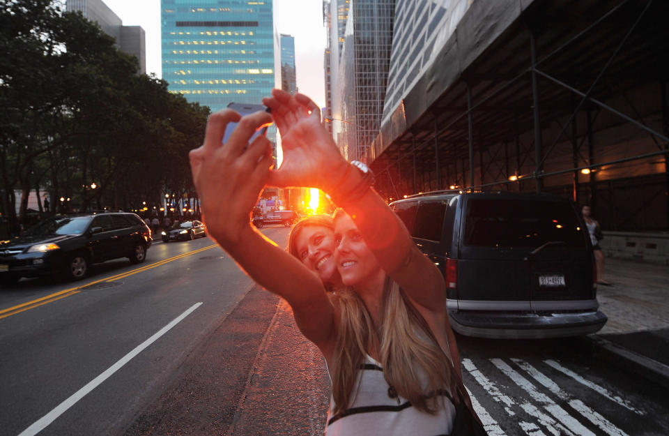 Two women photograph themselves during the "Manhattanhenge" sunset on July 13, 2011 in New York City. This semiannual occurrence was a half-sun Manhattanhenge, in which the setting sun aligns east-west with the street grid of the city. (Photo by Michael Loccisano/Getty Images)