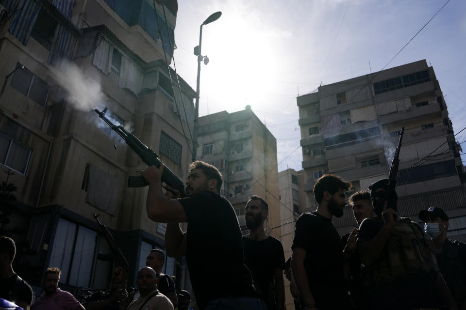 Supporters of the Shiite Amal group fire weapons in the air during the funeral processions of Hassan Jamil Nehmeh, who was killed during Thursday clashes, in the southern Beirut suburb of Dahiyeh, Lebanon, Friday, Oct. 15, 2021. Dozens of gunmen opened fire in the air Friday south of Beirut during the funeral of persons killed in hours of gun battles between heavily armed gunmen the day before that left seven people dead and terrorized the residents of Beirut. (AP Photo/Hassan Ammar)