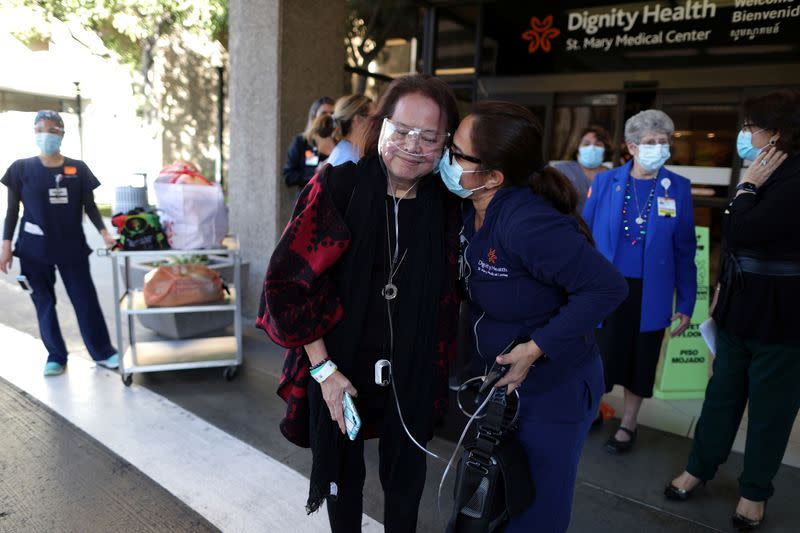 Intensive Care Unit Nurse Merlin Pambuan, is hugged by hospital staff as she walks out of the hospital where she spent 8 months with the coronavirus disease in Long Beach