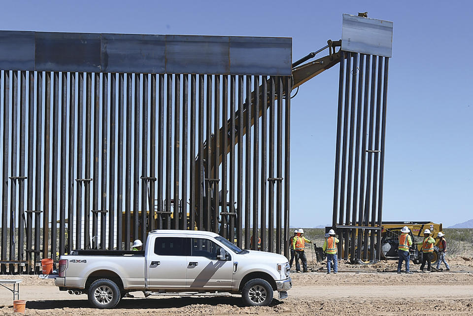 FILE - In this March 24, 2020 file photo, a new section of 30-foot-high "bollard style wall" is lifted into place at a construction site south of Yuma, Ariz., near the border between the United States and Mexico. The federal government is proceeding with plans for the border wall even as communities where construction is ongoing protest the presence of workers, according to court documents. On Friday, April 24, 2020 U.S. Rep. Raul Grijalva, D-Arizona, and others held a press call to persuade the government to at least temporarily stop construction. (Randy Hoeft/The Yuma Sun via AP, File)
