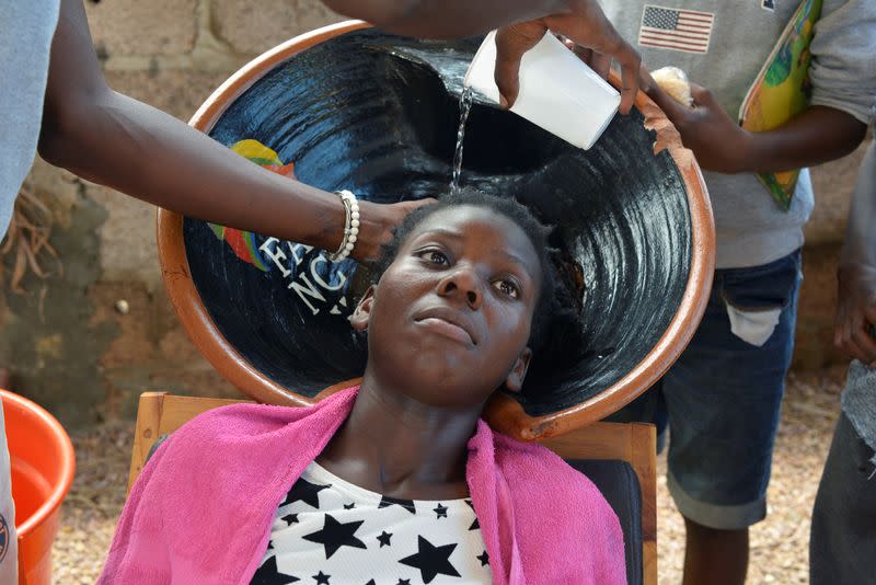 Cadino Chipanga washes a customer's dreadlocks at his salon in Mafalala, on the outskirts of Maputo