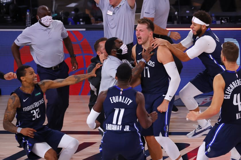 Dallas Mavericks' Luka Doncic (77) celebrates his winning three-point basket with teammates .