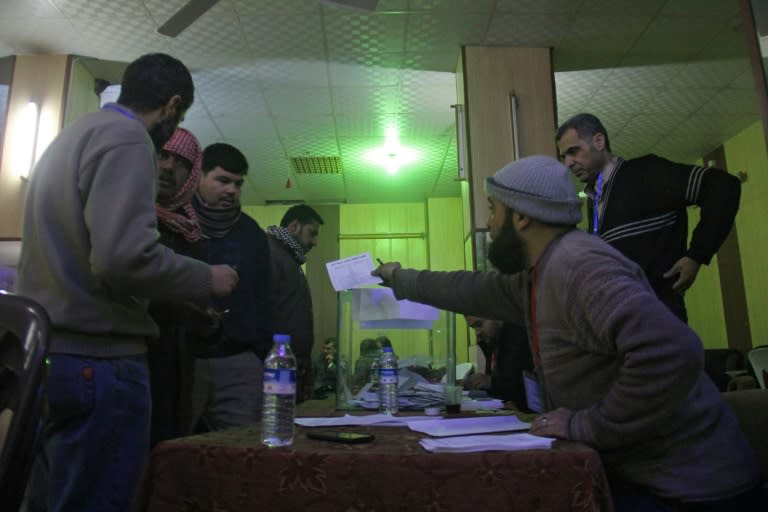 Syrian men queue to cast their vote at a polling station in the city of Idlib as they elect the city's first civilian council, two years after it was overrun by rebels and jihadists, on January 17, 2017