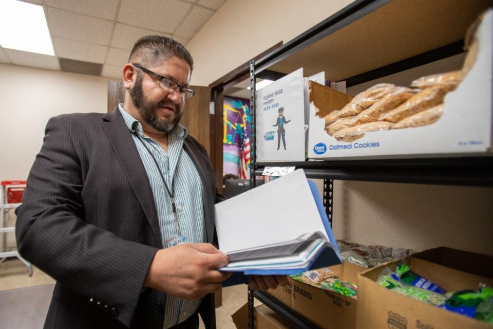 Felix Fernandez, coordinator of the Tejano Food Pantry, checks student request forms on Wednesday, Oct. 26. Students can indicate food preferences when requesting assistance. (Corrie Boudreaux/El Paso Matters)