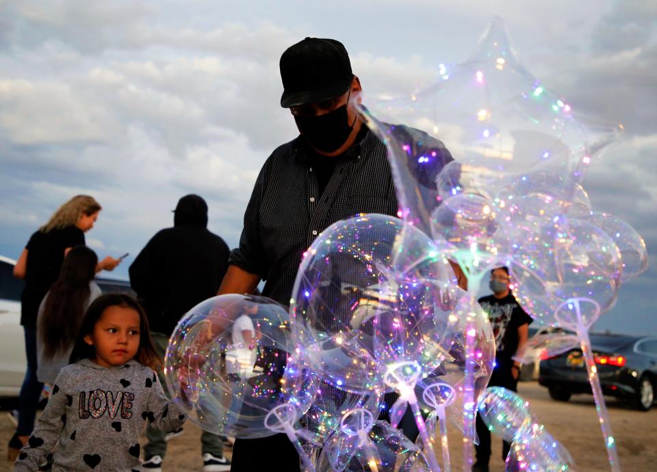 Shiprock resident Lloyd Smith, center, helps a young customer select an LED balloon before the fireworks show starts on July 1 in Shiprock.