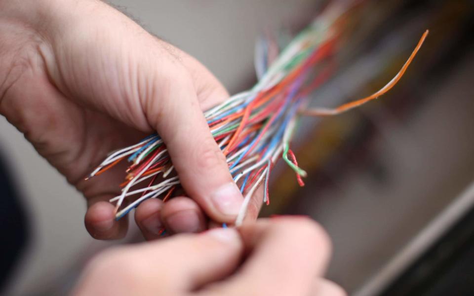 An engineer for BT Openreach part of the BT Group Plc works on phone cables in a network box  - Credit: Chris Ratcliffe/Bloomberg 