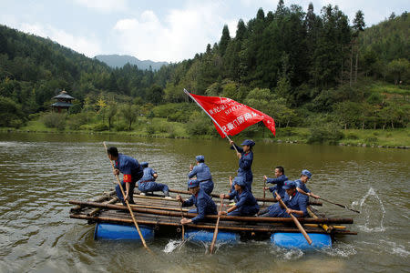 Participants dressed in replica red army uniforms row a raft across a lake during a Communist team-building course extolling the spirit of the Long March, organised by the Revolutionary Tradition College, in the mountains outside Jinggangshan, Jiangxi province, China, September 14, 2017. REUTERS/Thomas Peter