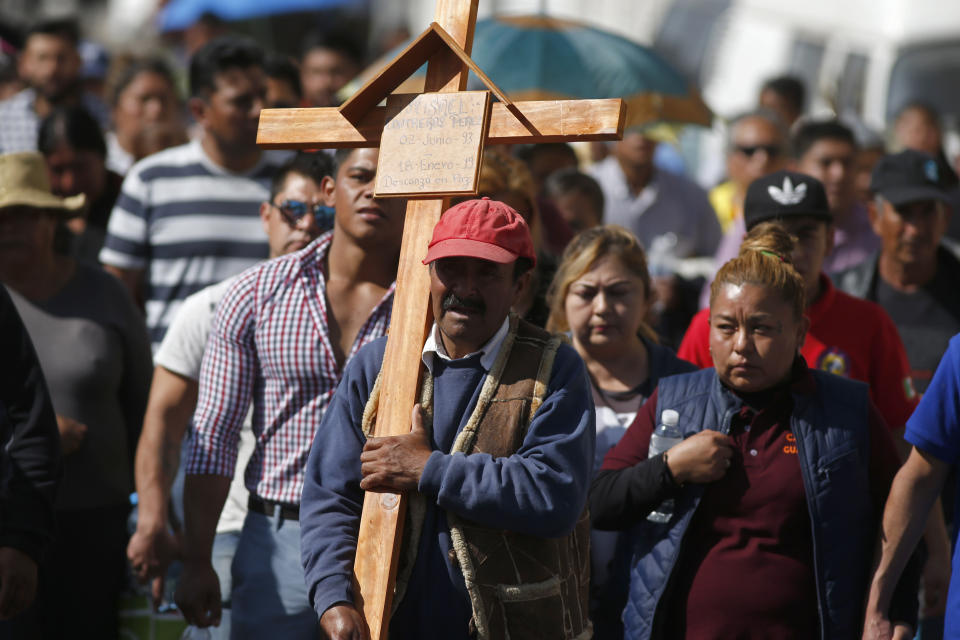 A man carries a cross during the funeral procession of a person who died when a gas pipeline exploded in the village of Tlahuelilpan, Mexico, Sunday Jan. 20, 2019. A massive fireball that engulfed locals scooping up fuel spilling from a pipeline ruptured by thieves in central Mexico killed dozens of people and badly burned dozens more on Jan. 18. (AP Photo/Claudio Cruz)