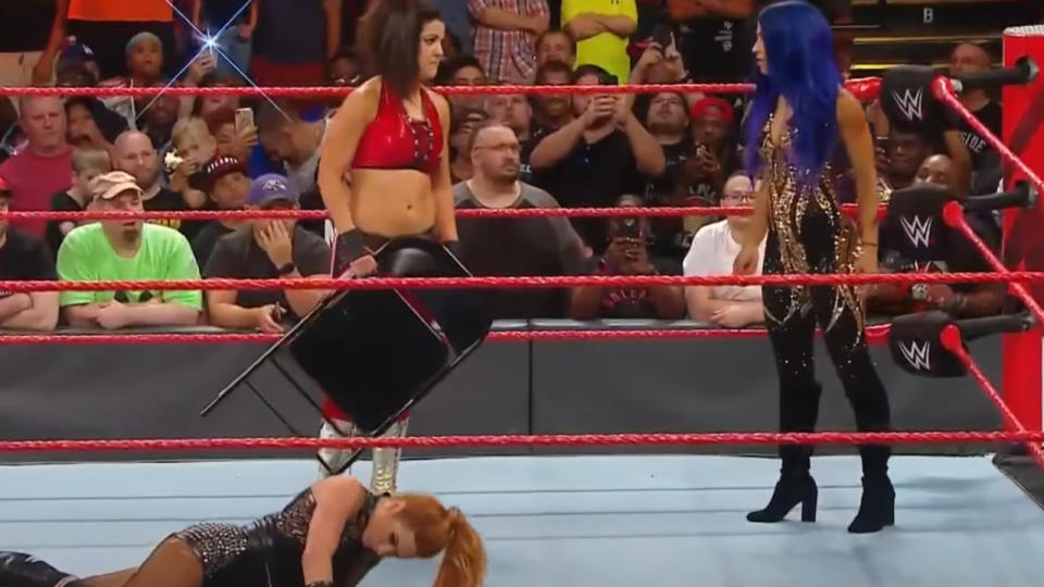 Bayley holds a chair just before hitting Becky Lynch