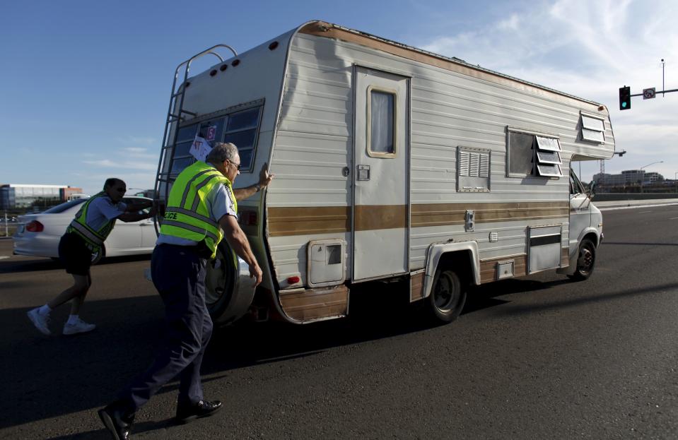 Retired Senior Volunteer Patrol member Steve Rubin and Robert Stewart (R) push a stalled motor home off a highway and out of traffic during their patrol in San Diego, California, United States April 30, 2015. (REUTERS/Mike Blake)